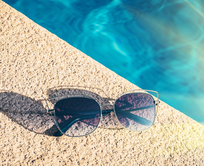 Óculos de sol na borda da piscina